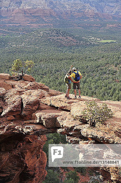 Hiking couple viewing from arched rock formation  Sedona  Arizona  USA