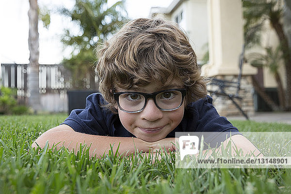 Porträt eines kleinen Jungen  der auf dem Kopf im Gras liegt  Nahaufnahme