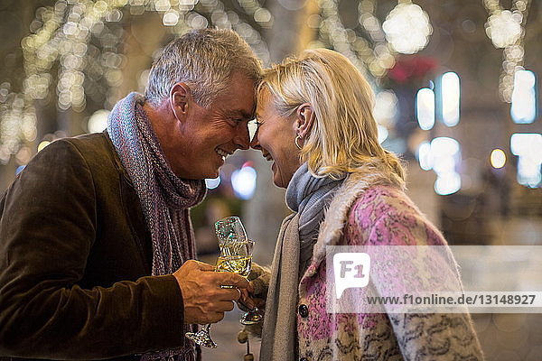 Älteres Paar stößt mit Champagner auf einer von Bäumen gesäumten Allee an Weihnachten an  Mallorca  Spanien
