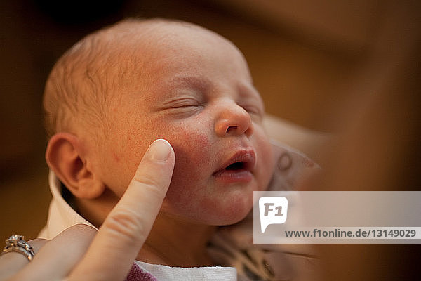 Mother touching newborn baby boy's face with finger