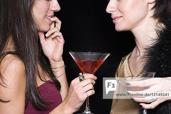 Zwei Frauen mit Cocktails in der Hand  Gesicht an Gesicht  in einem Nachtclub