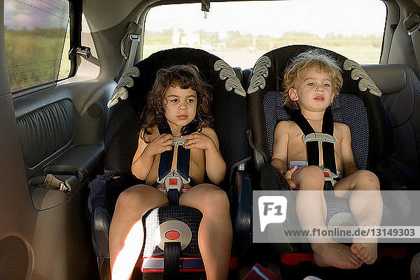 Brother and sister sitting in car seats