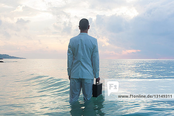 Businessperson standing in sea  rear view