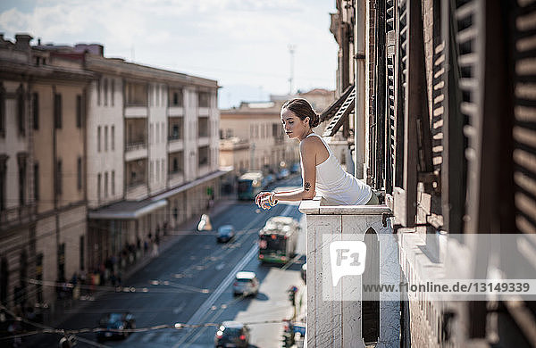 Junge Frau schaut über den Balkon auf die Straße  Castiadas  Sardinien  Italien