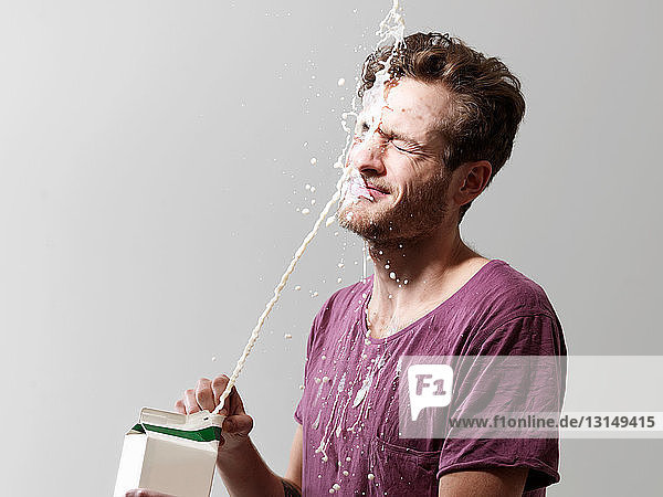 Young man spilling milk from carton  studio shot