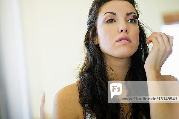 Frau trägt Make-up mit kleinem Pinsel auf