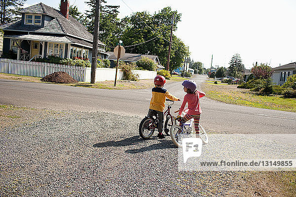 Brother and sister on bicycles in neighborhood