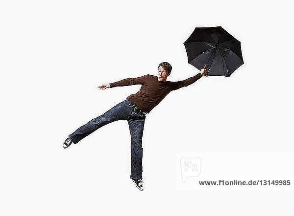 Mann mit Regenschirm weggepustet