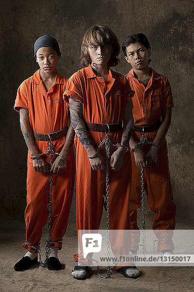 Studio portrait of three boys in handcuffs and chains
