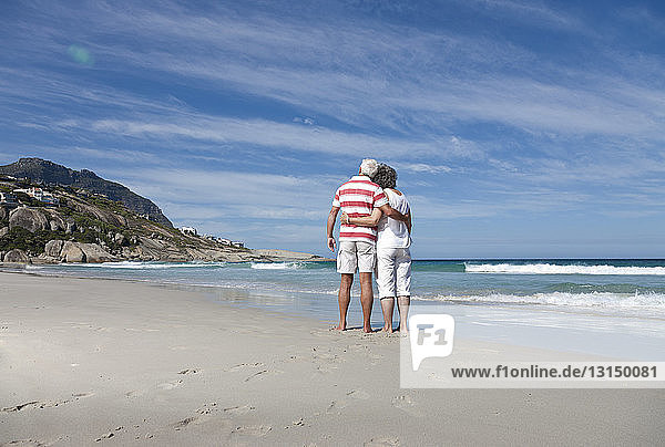 Älteres Paar umarmt sich am Strand