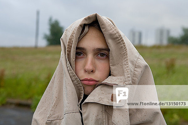 Sad looking teenage girl with coat covering head