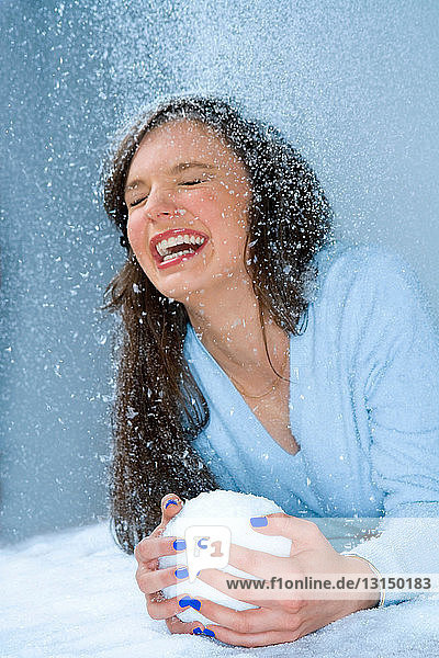 Frau lacht im Schnee  hält Schneeball