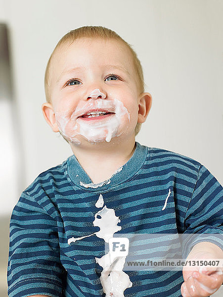 Kleiner Junge mit Joghurt im Gesicht