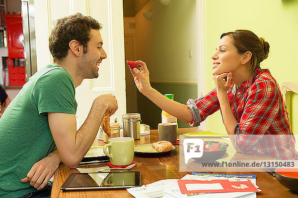 Young couple at breakfast  woman feeding man strawberry