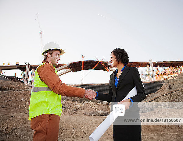 Mann und Frau schütteln sich auf der Baustelle die Hände