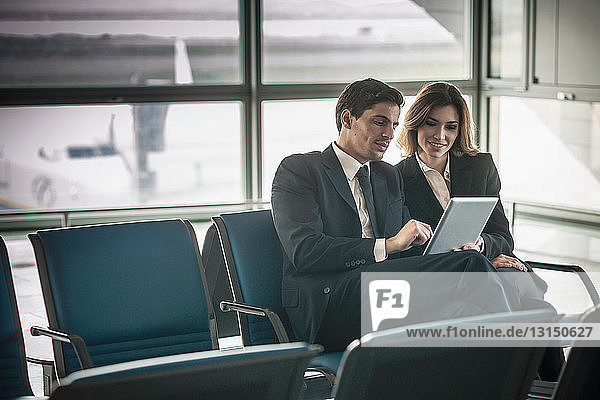 Geschäftsleute nutzen digitale Tabletten in der Abflughalle eines Flughafens