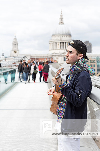 Young man busking on Millennium Bridge  London  UK