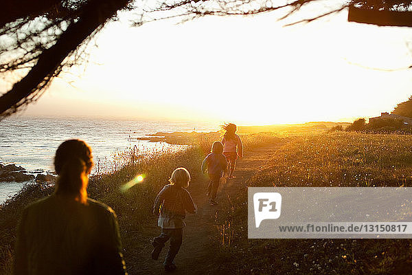 Familienspaziergang an der Küste bei Sonnenuntergang