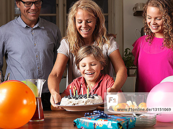 Mother giving boy birthday cake at party