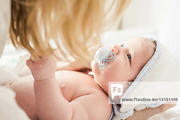 Mid adult mother holding baby in towel