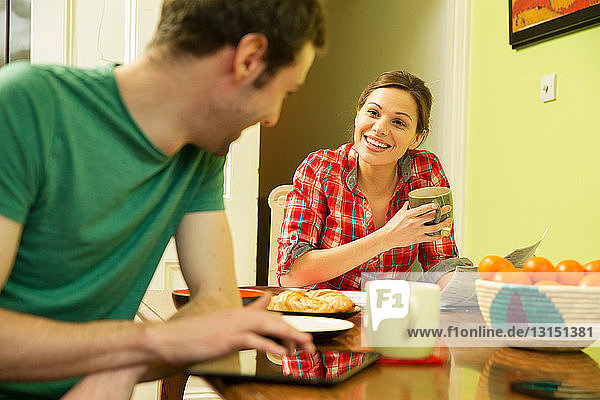Junges Paar beim Frühstück  Mann mit digitalem Tablet
