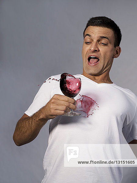 Mann stößt sein Glas Wein um