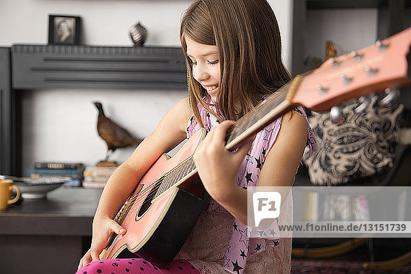 Girl playing acoustic guitar at home