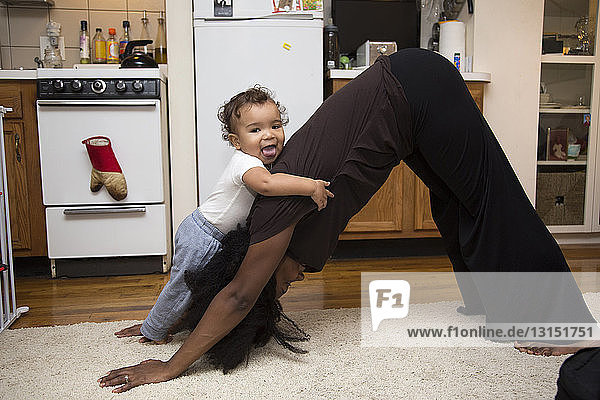 Mid erwachsene Frau übt auf Teppich mit Kleinkind Tochter