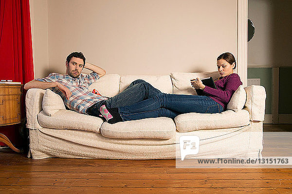 Junges Paar sitzt auf Sofa