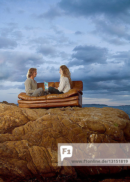 Paar mit Laptop auf der Couch am Strand