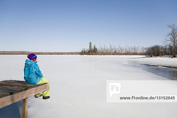 Frau entspannt sich auf dem Dock am zugefrorenen See