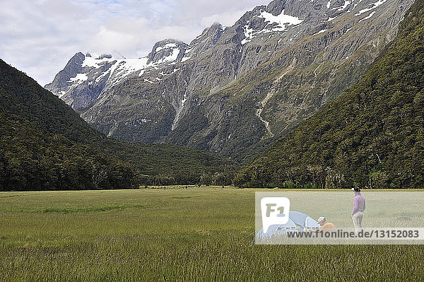 Paar zeltet auf einem Feld mit Bergen  Neuseeland