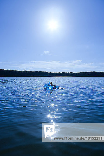 Boy swimming in lake with an inflatable dolphin  Brandenburg  Germany