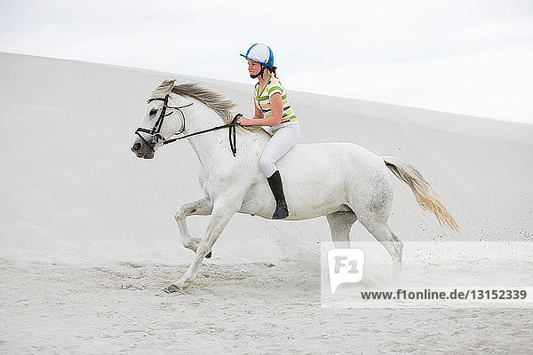 Junges Mädchen reitet auf einem Pferd am Strand