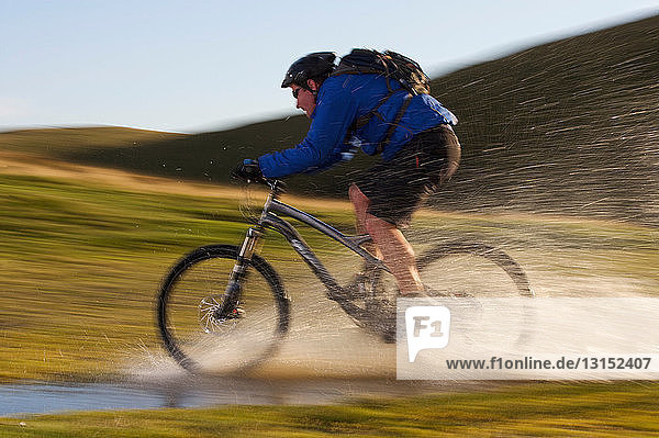 Mountain biker riding through water.