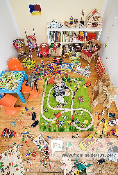 Junge spielt in einem mit Spielzeug vollgestopften Zimmer