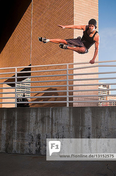 Athlete jumping over urban wall