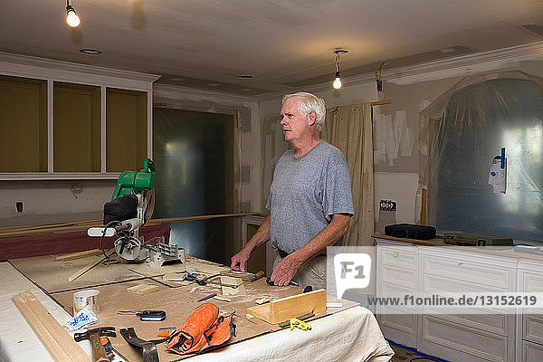 Senior man doing DIY in kitchen