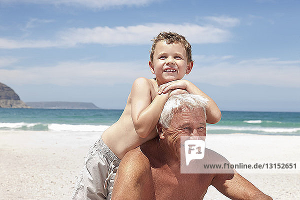 Älterer Mann mit Enkel am Strand