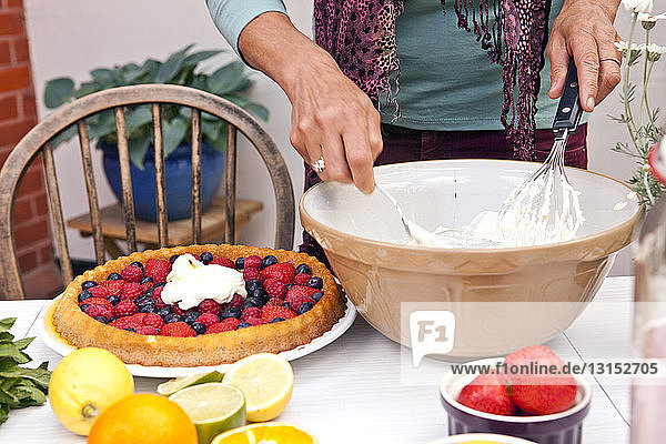 Abgeschnittene Aufnahme einer reifen Frau  die auf einer Gartenparty Obstkuchen zubereitet
