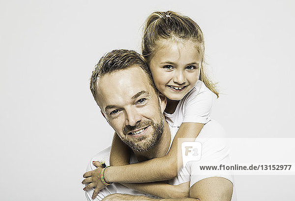 Studio portrait of girl getting piggyback from father