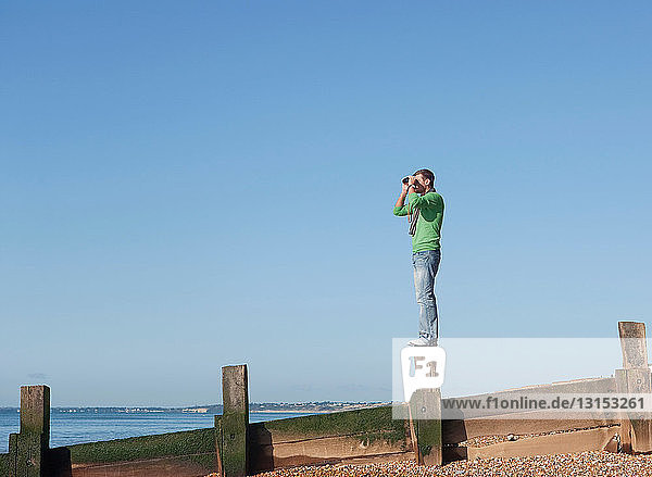 Man with binoculars looking out to sea