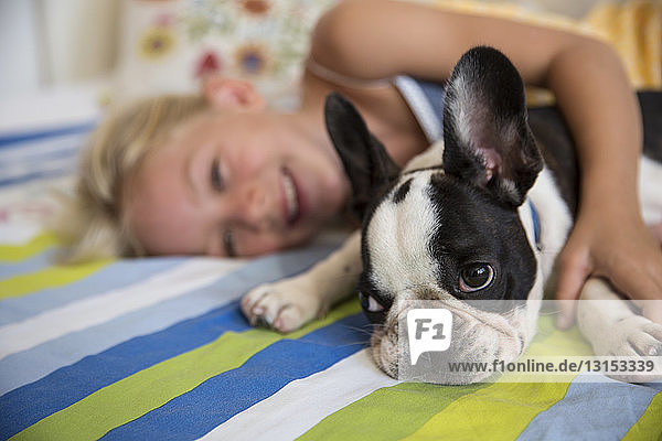 Porträt eines niedlichen Hundes und eines Mädchens auf dem Bett liegend