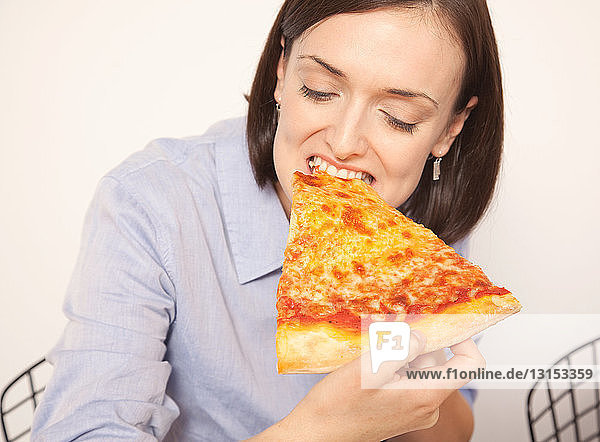 Mittlere erwachsene Frau genießt Pizzastück