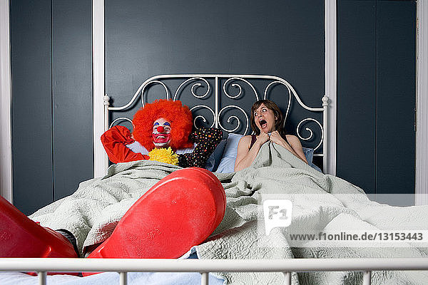 Woman screaming as she realises she is in bed with a clown