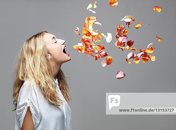 Young woman with mouth open an petals floating in mid air