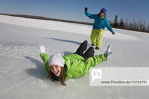 Zwei Frauen rutschen auf gefrorenem See