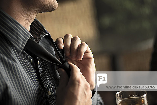 Close up of businessman loosening tie in a wine bar