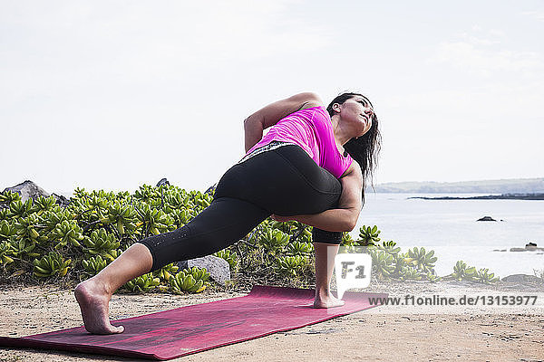 Woman practicing yoga pose on beach  Hawea Point  Maui  Hawaii  USA