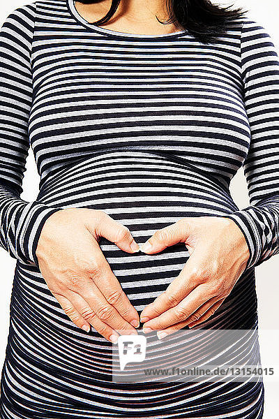 Pregnant mid adult woman in striped dress against white background